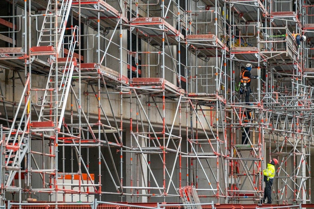 To arbeidere ved et omfattende stillas på en byggeplass